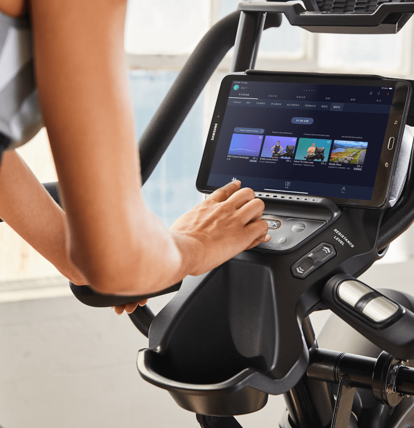 Woman using a fitness machine with a tablet